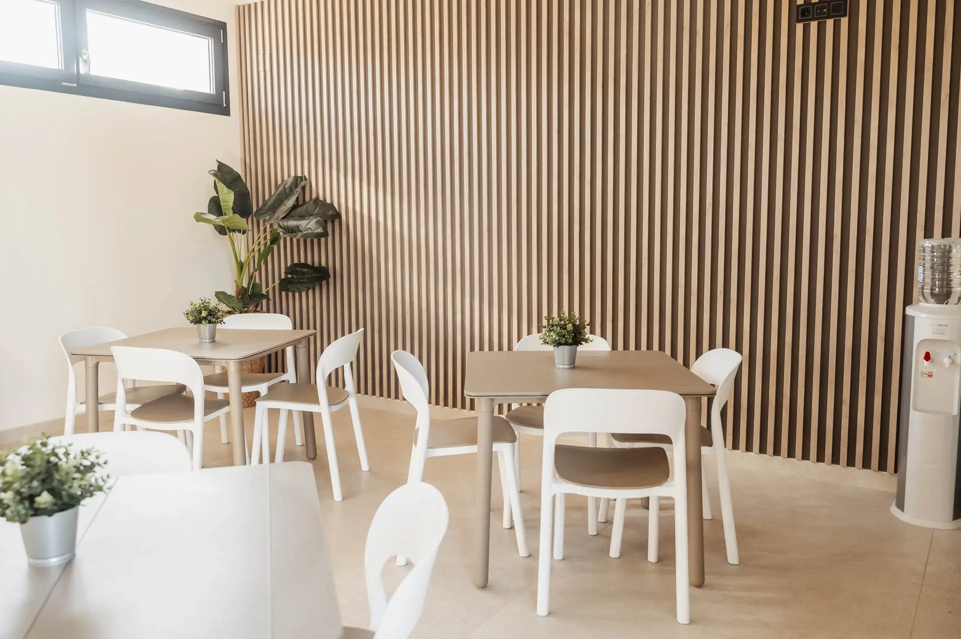 Cafetería con mesas claras y pared de listones de madera