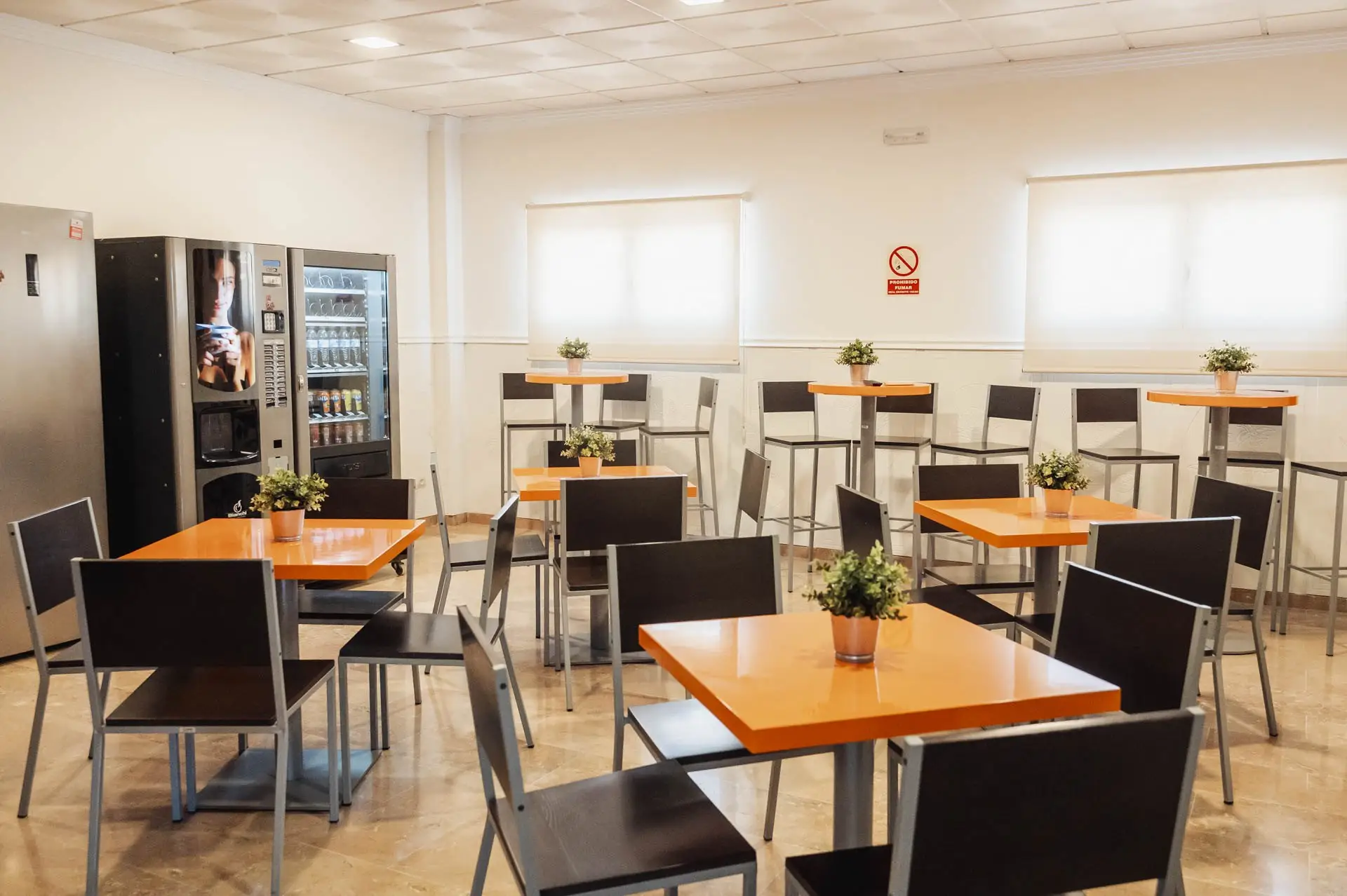 Cafetería con mesas y máquinas de café y bebidas