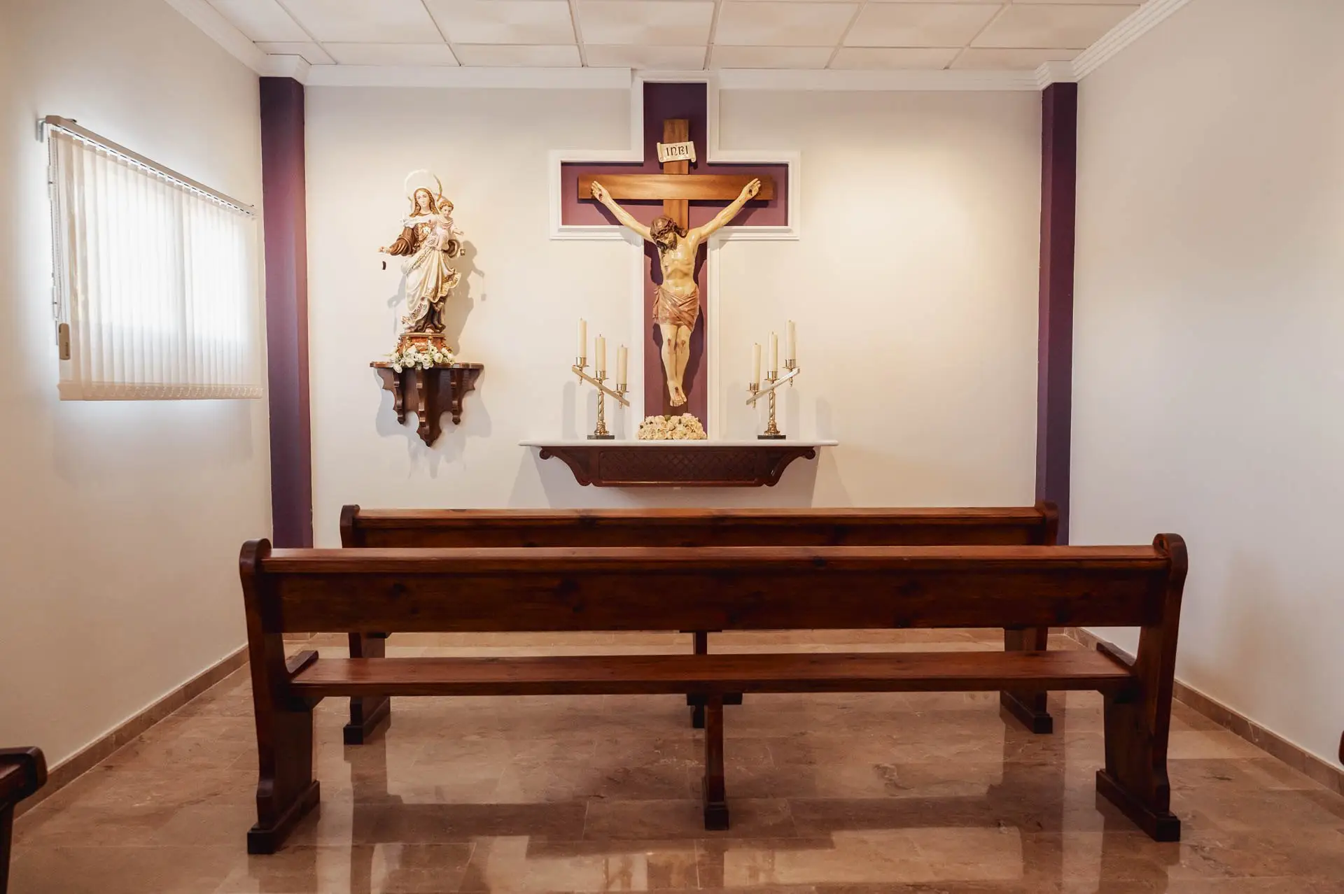 Capilla con banco de madera, crucifijo e imagen de la Virgen